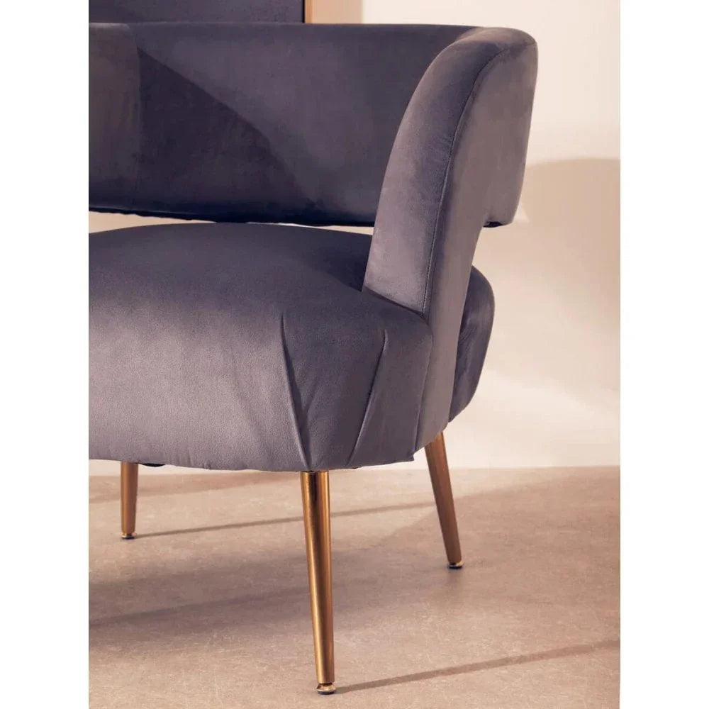 Grey velvet accent chair with gold metal legs, close-up view of seat and armrest