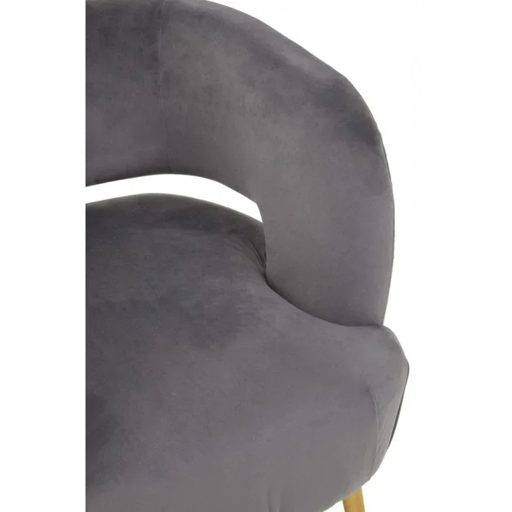Close-up of grey velvet chair with curved backrest and gold leg