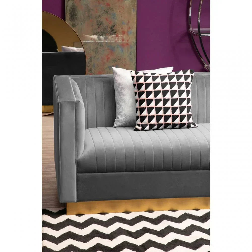 Grey velvet sofa with gold base, patterned cushions, and chevron rug in modern living room