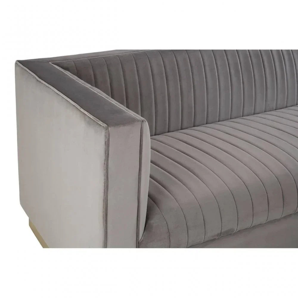 Grey velvet sofa with vertical channel tufting and square armrest, close-up view