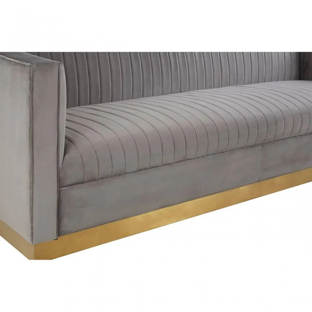 Grey velvet sofa with vertical stitched upholstery and gold metal base, side angle view
