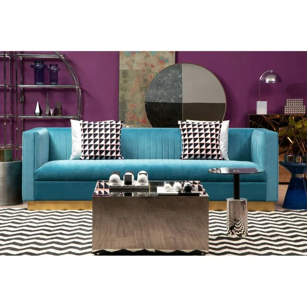 Blue velvet sofa with geometric cushions, mirrored coffee table, and zigzag rug in modern lounge