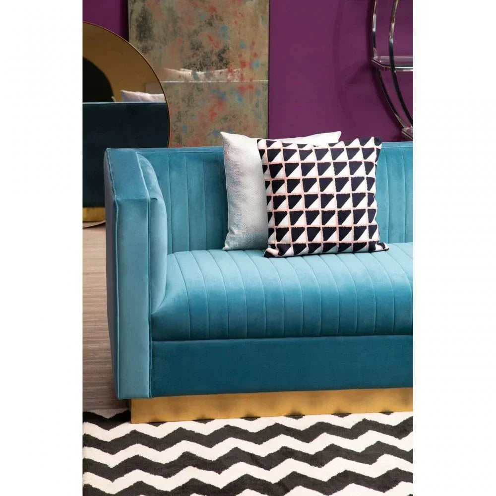 Blue velvet sofa with gold base, geometric cushion, and black chevron rug in modern room