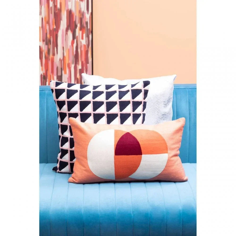 Geometric patterned cushions on blue velvet sofa with peach and black color accents