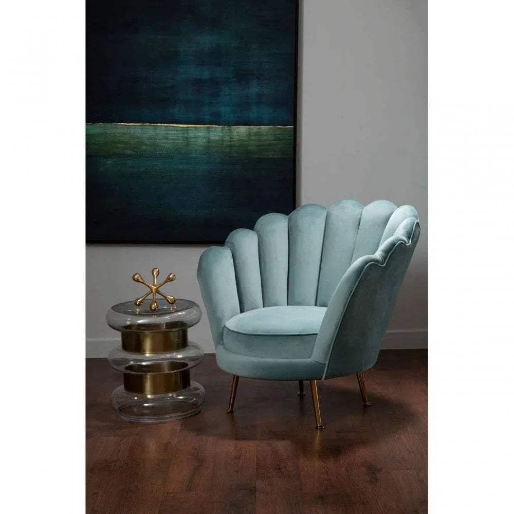 Blue velvet accent chair with shell backrest and gold legs beside modern side table