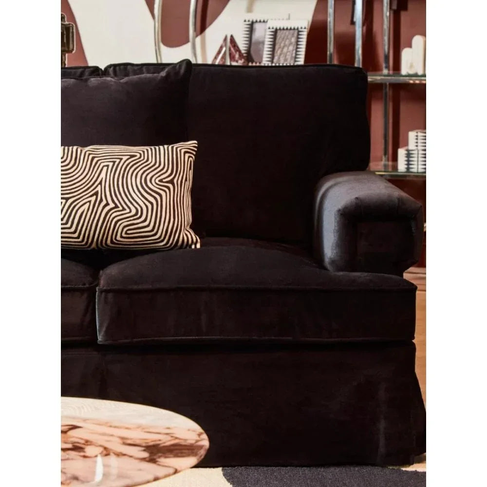 Black velvet sofa with modern patterned cushion in stylish living room setting