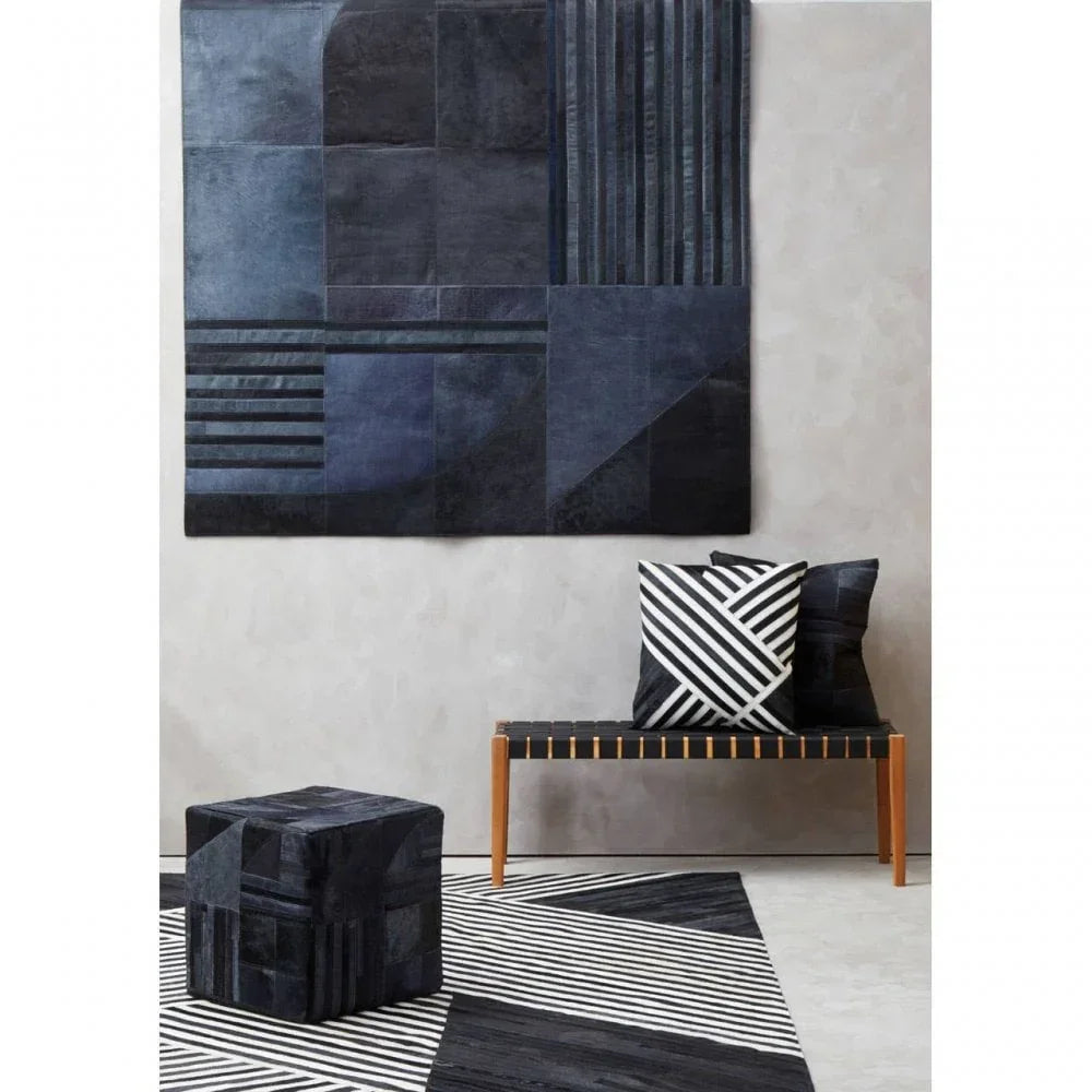 Modern geometric rug, bench with black and white cushions, dark cube ottoman in living room
