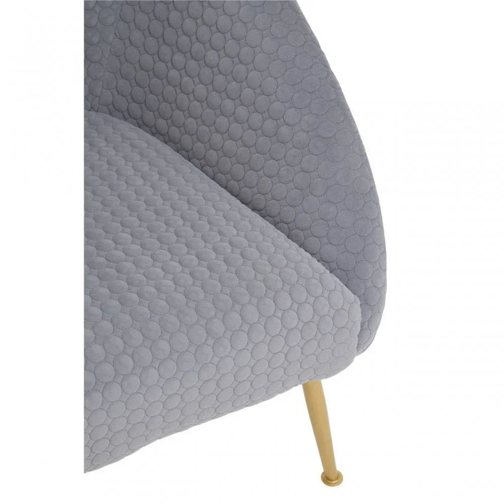 Grey textured armchair seat with gold metal leg and circular pattern upholstery close-up