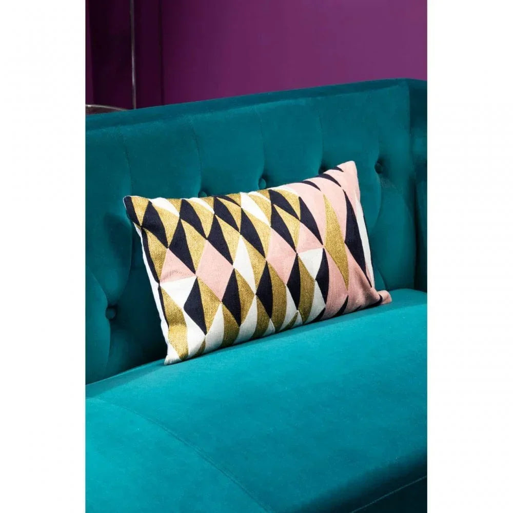 Geometric pattern cushion on teal velvet sofa with tufted detail against purple wall