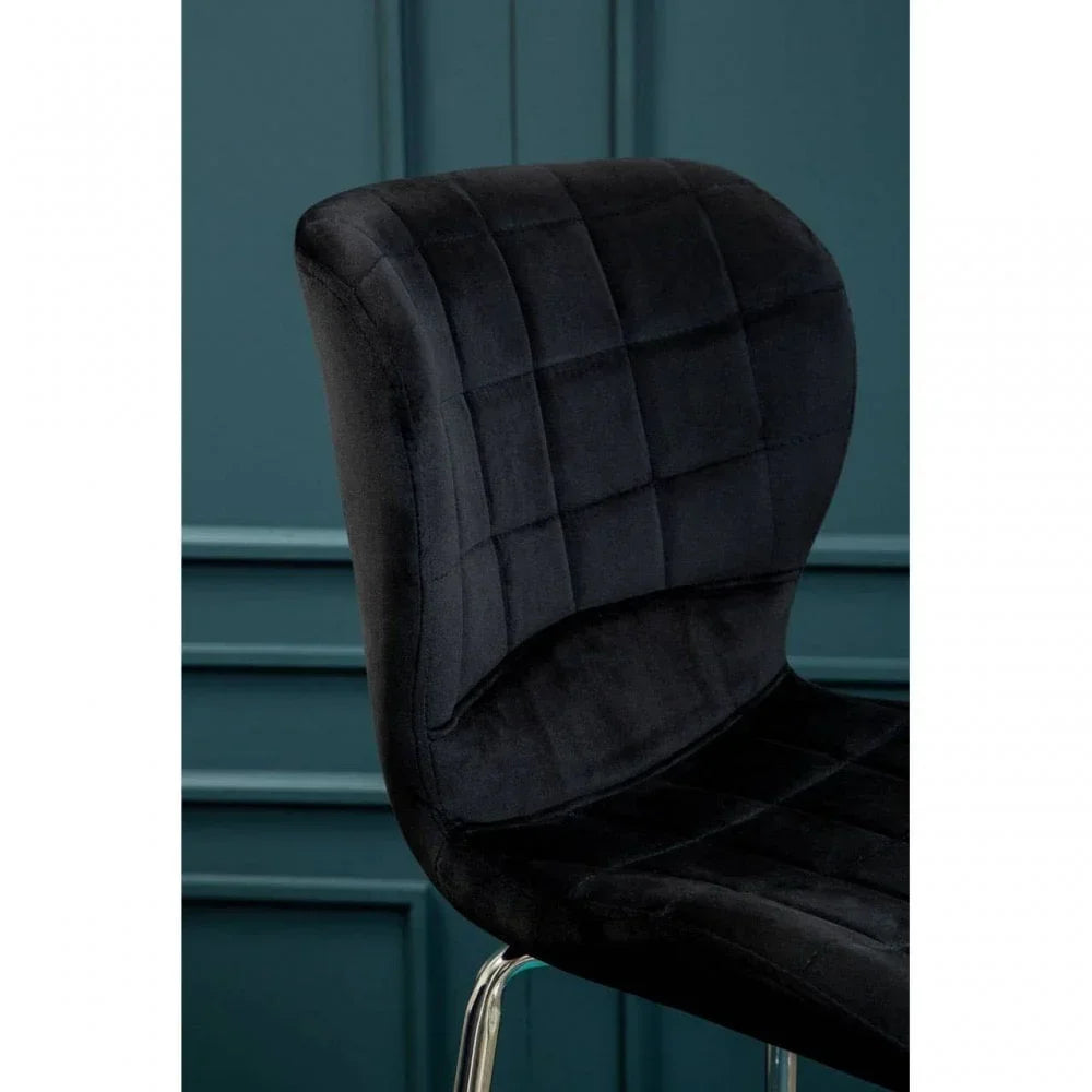 Black velvet dining chair with chrome legs and square stitched upholstery, side angle view