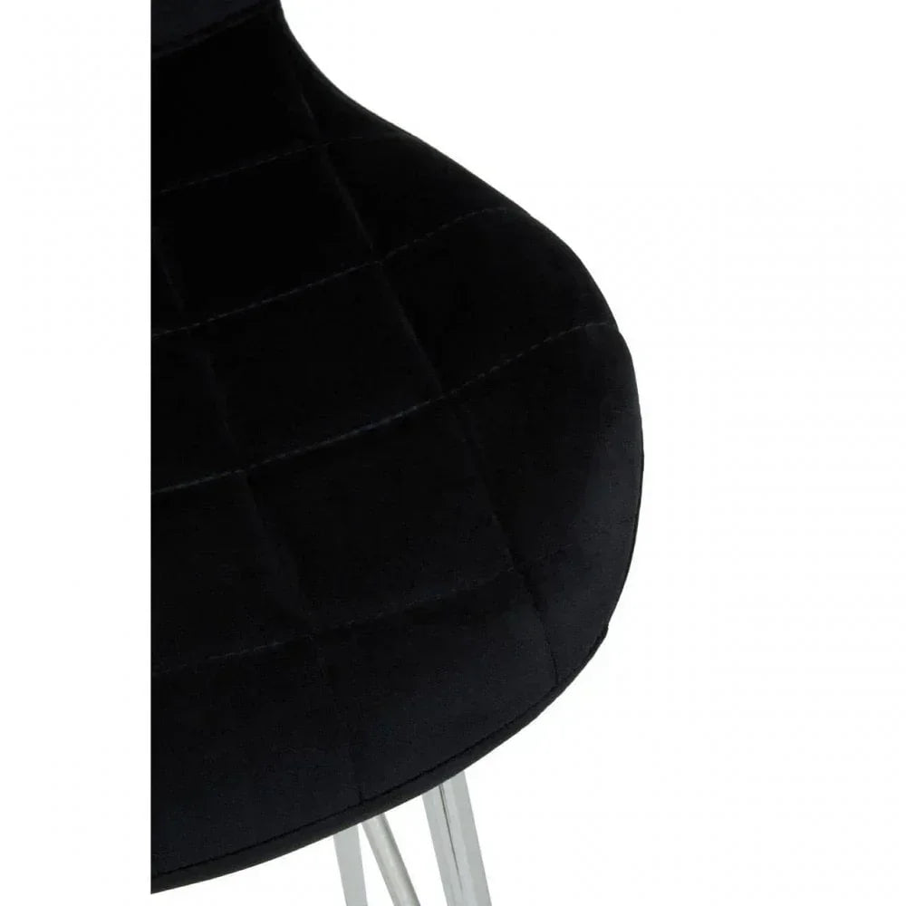 Black velvet dining chair seat with chrome legs and stitched square detail, close-up view