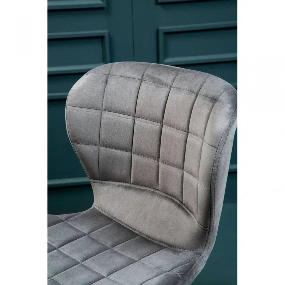 Grey velvet dining chair with quilted upholstery and curved backrest detail