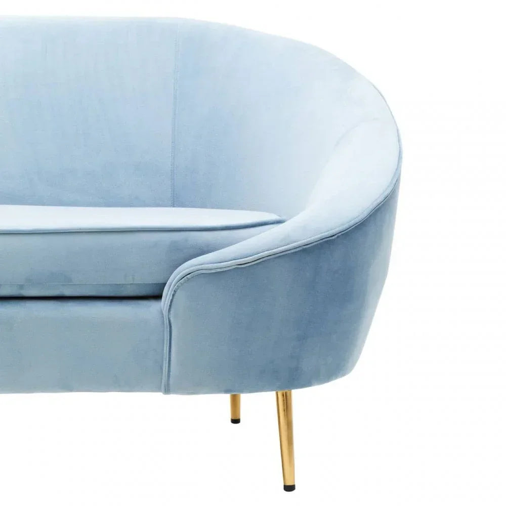 Light blue velvet sofa with curved backrest and gold metal legs, close-up view