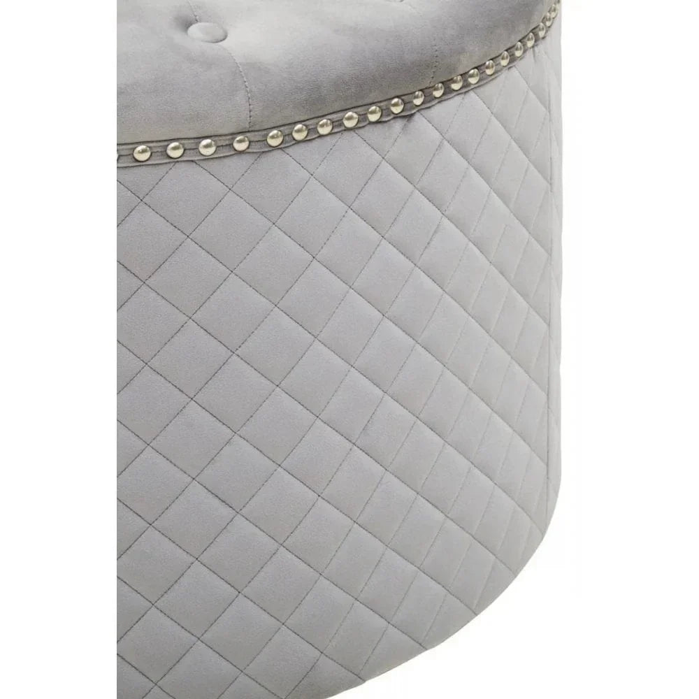 Close-up of grey ottoman with diamond quilted fabric and studded trim detail