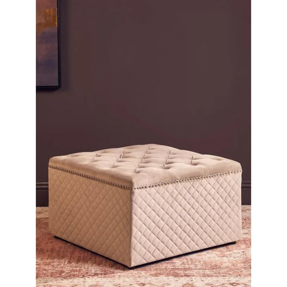 Beige upholstered ottoman with tufted top and quilted sides on patterned rug