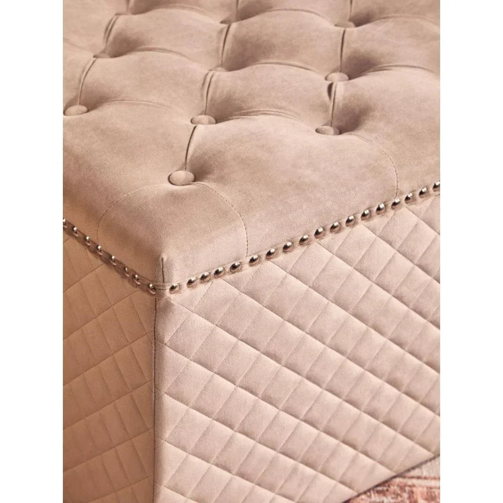 Beige upholstered ottoman with tufted top, quilted sides, and silver nailhead trim detail
