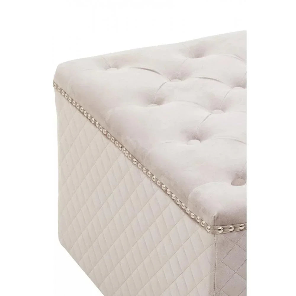 Cream upholstered ottoman bench with button-tufted top and silver studded trim corner