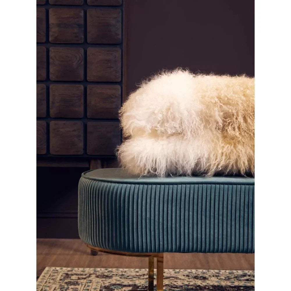 Teal velvet ottoman with gold legs and cream sheepskin throw in modern living room