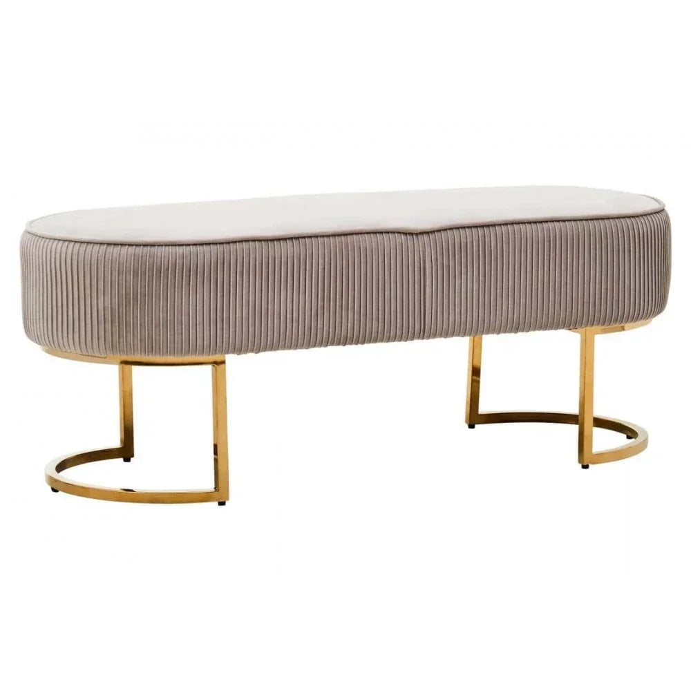 Beige velvet bench with gold metal legs and ribbed detailing, shown from a side angle