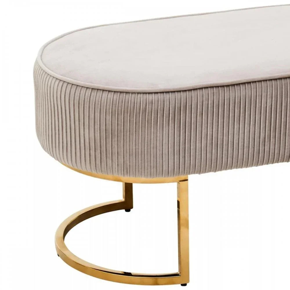 Beige velvet ottoman with ribbed sides and gold metal base, close-up side view