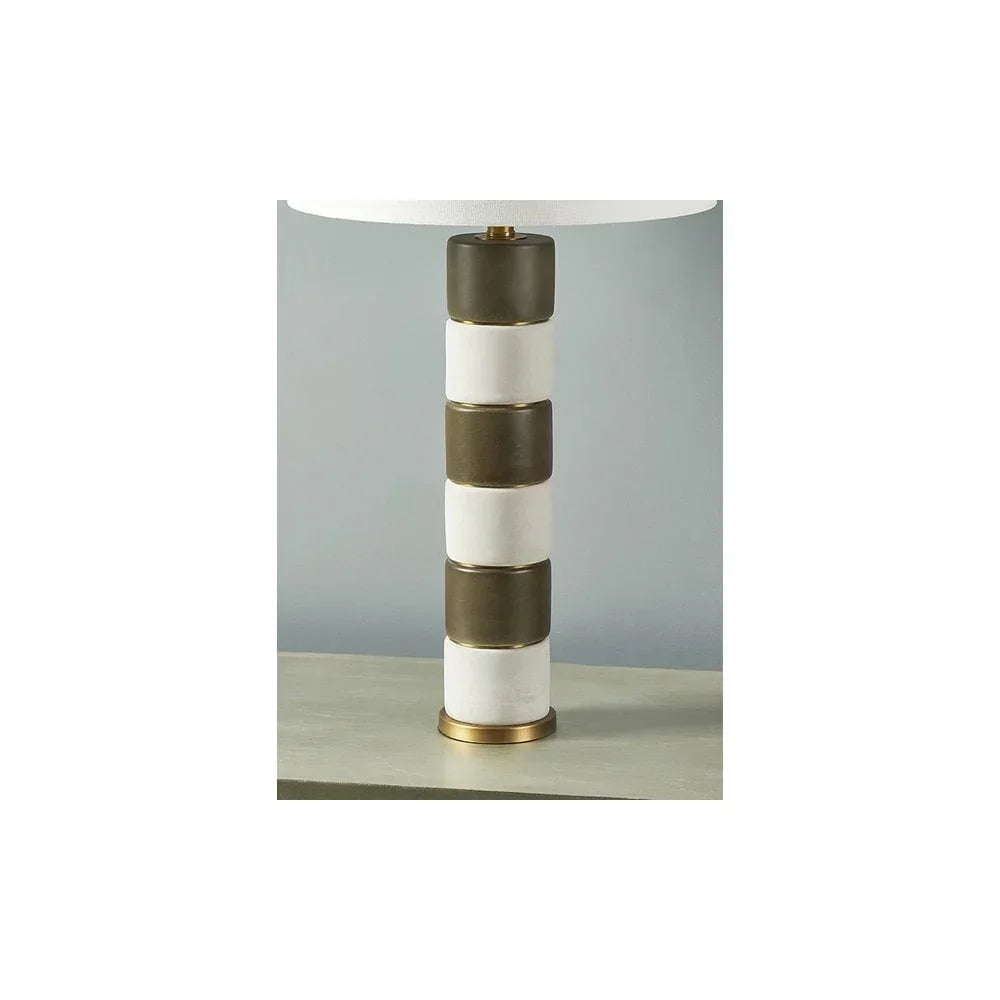 Modern table lamp with stacked white and bronze ceramic base on a light wooden surface
