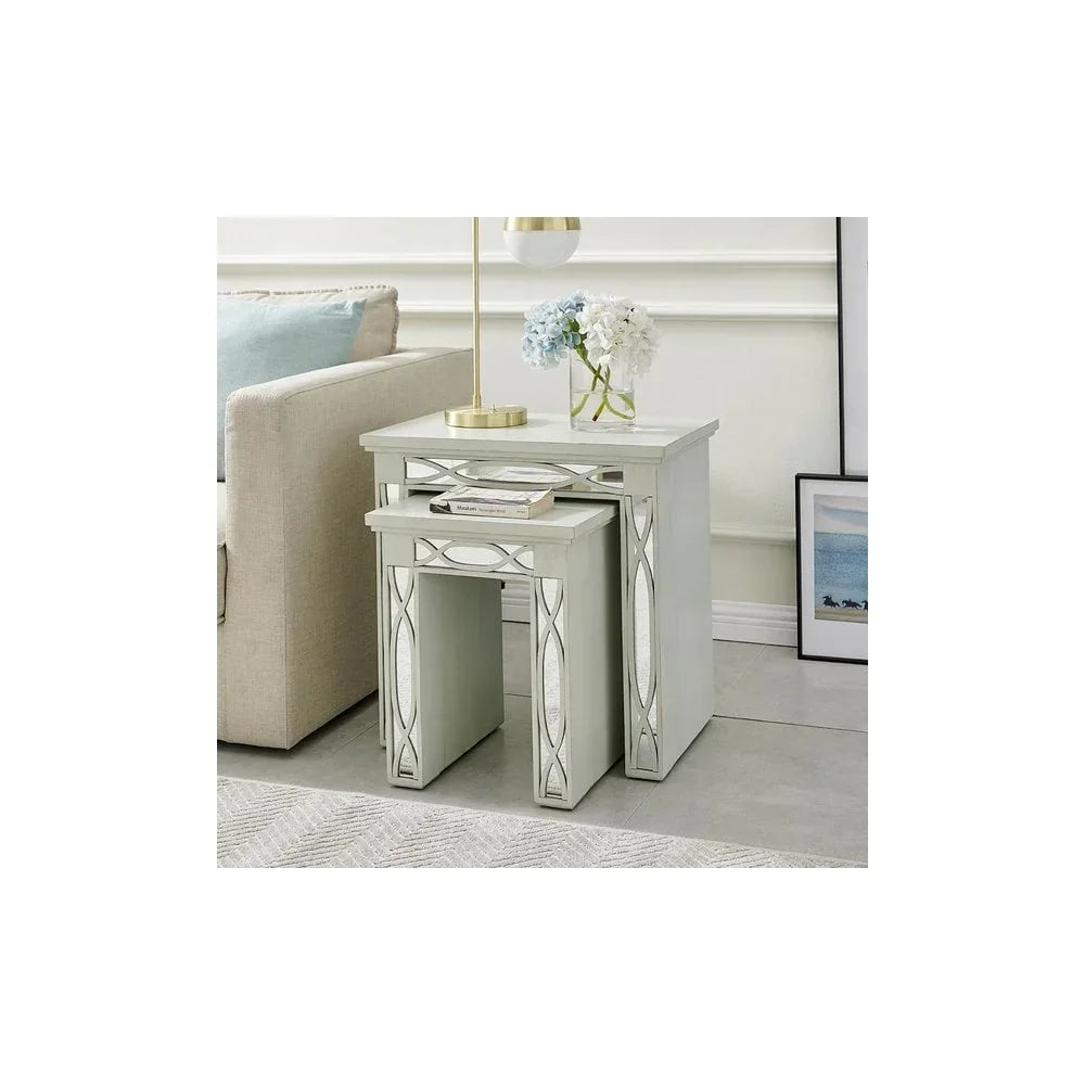 Mirrored nesting tables with decorative panels beside sofa, styled with lamp and vase