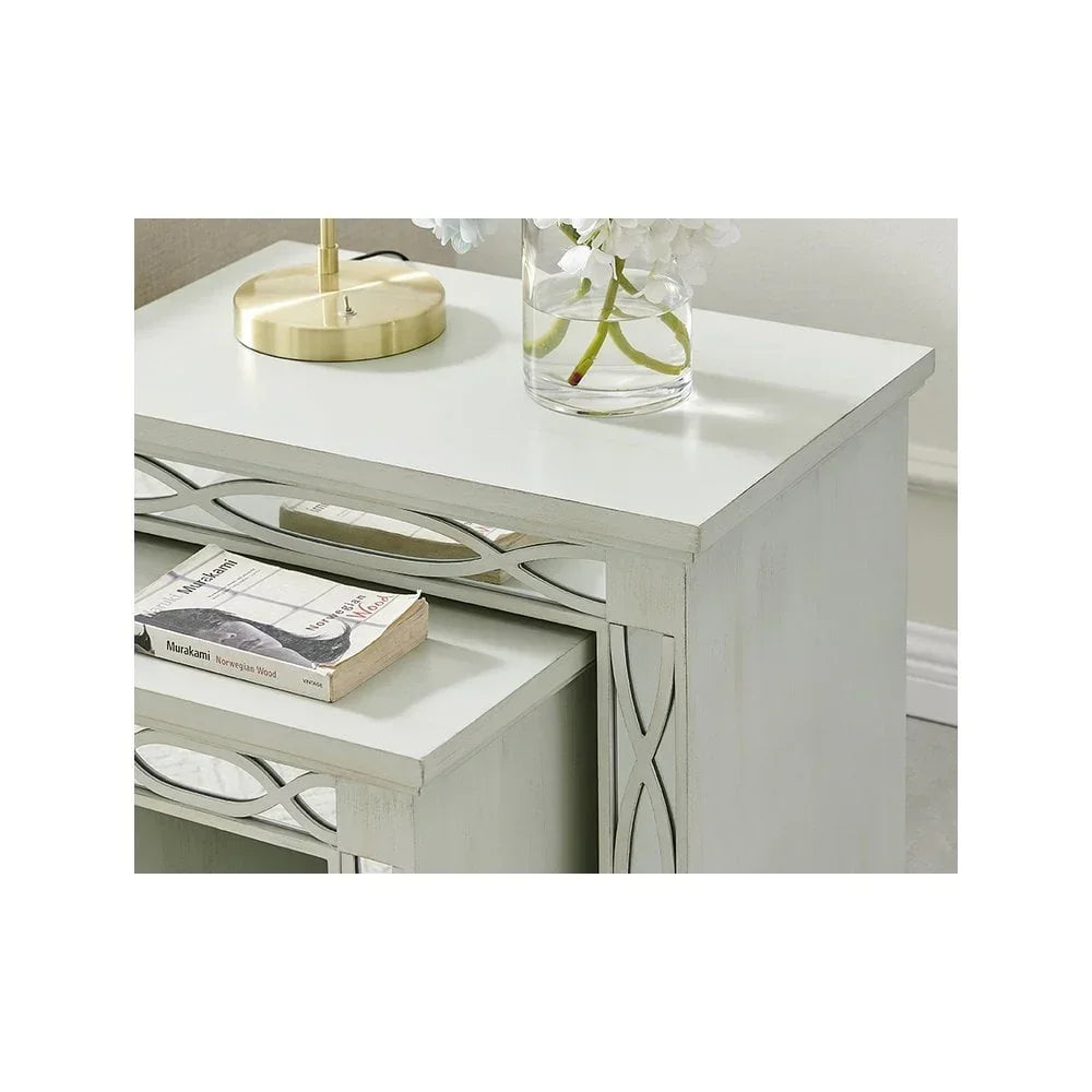 White wooden nesting tables with mirrored trim, decorative lamp and vase on top surface