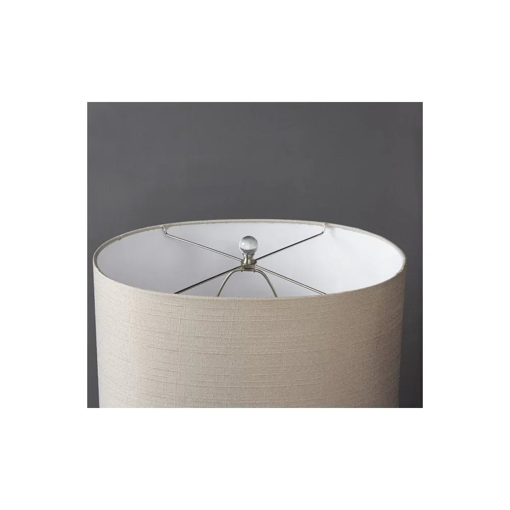 Beige fabric drum lampshade with metal frame and white inner lining against dark wall