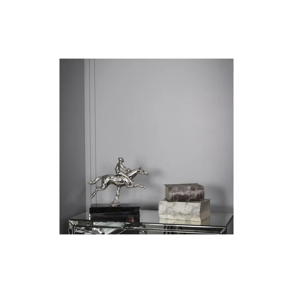 Silver horse and rider ornament on mirrored console table beside two decorative boxes