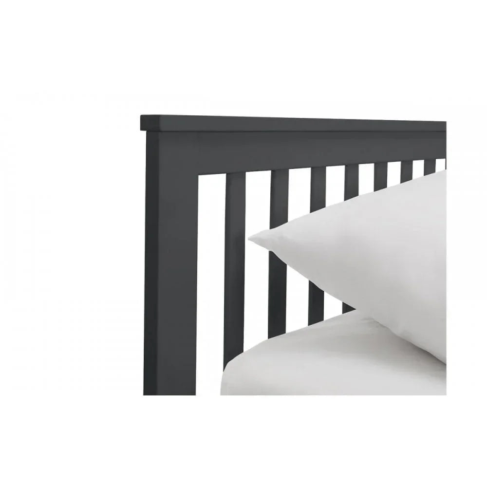 Black wooden bed frame with slatted headboard and white bedding, close-up angle