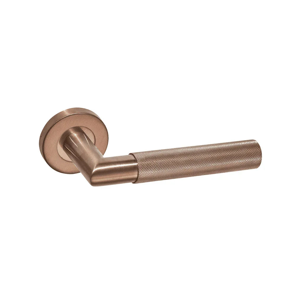 Brushed copper door handle with textured grip on round backplate