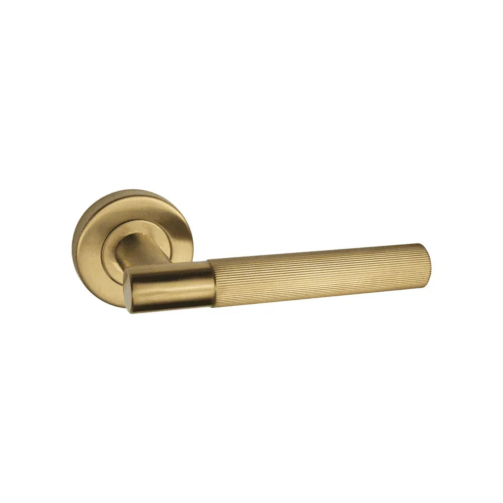 Brushed brass door handle with textured grip and round rose on white background