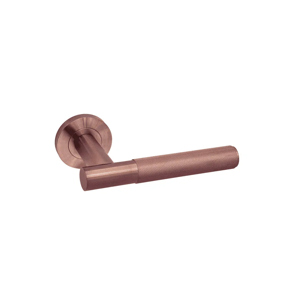 Brushed copper door handle with textured grip and round backplate on white background