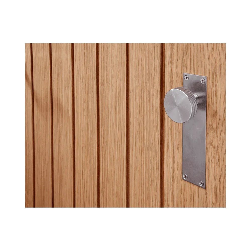 Modern stainless steel door handle on vertical panelled light oak door