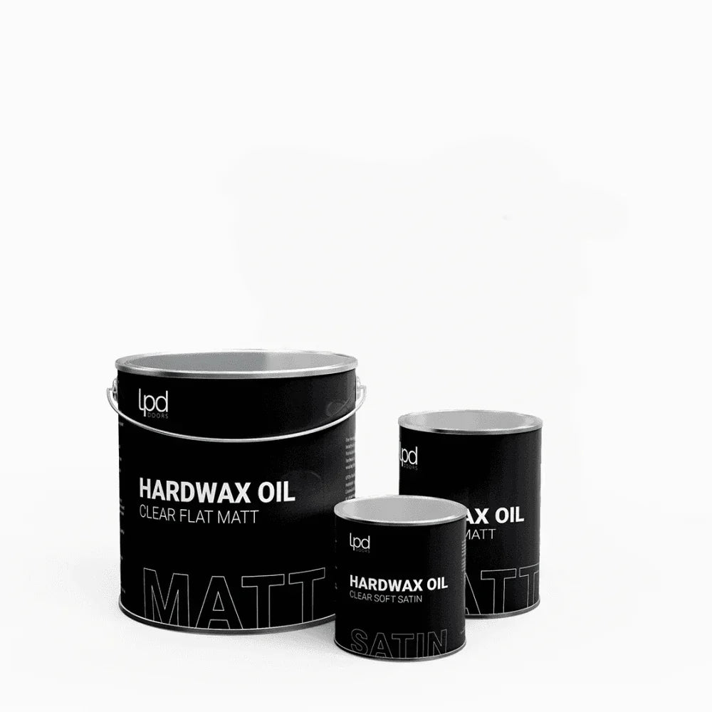 Three black hardwax oil tins in matt and satin finishes on white background