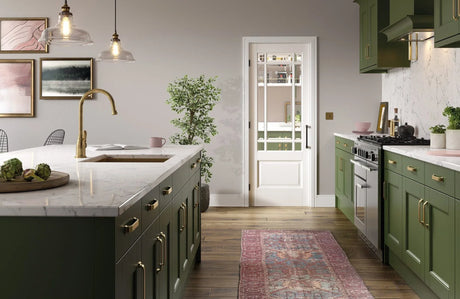 Green kitchen cabinets with marble worktops, brass handles, and modern appliances