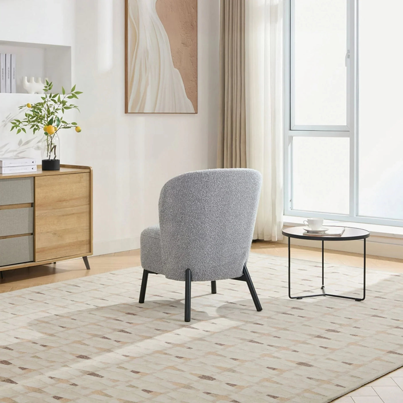 Ash grey accent chair with rounded backrest and black legs in modern living room setting