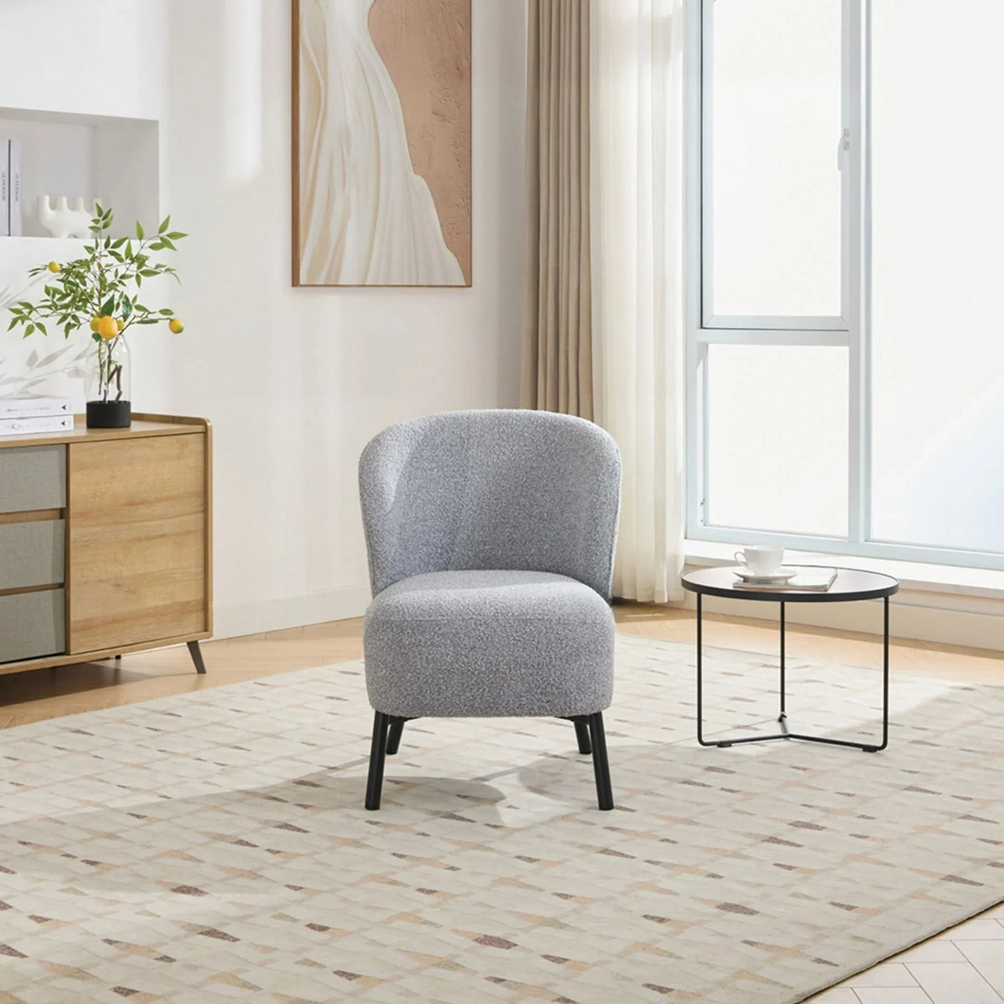 ash grey accent chair with curved backrest on patterned rug beside round coffee table in living room