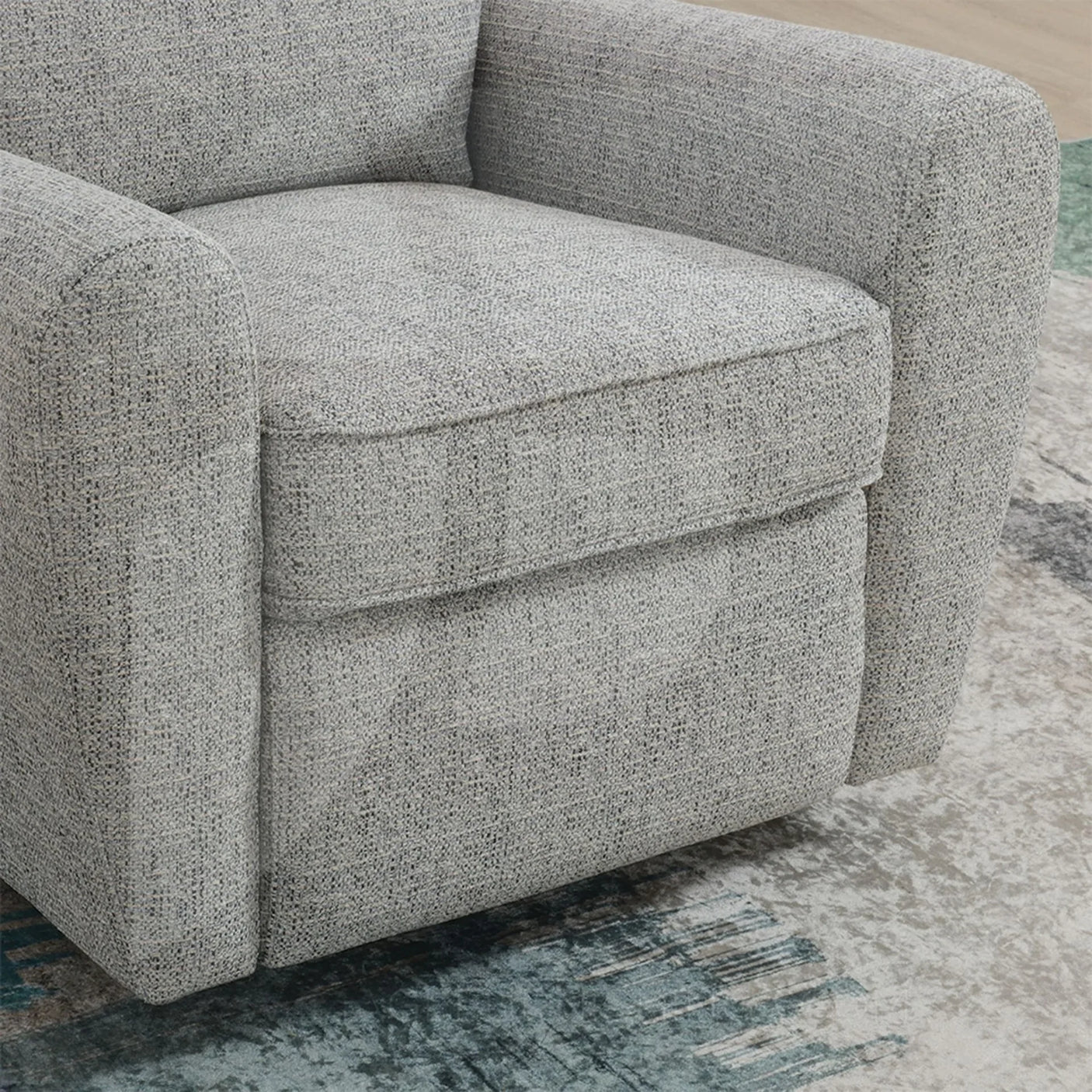 Close-up of grey fabric swivel chair with rounded arms on patterned rug