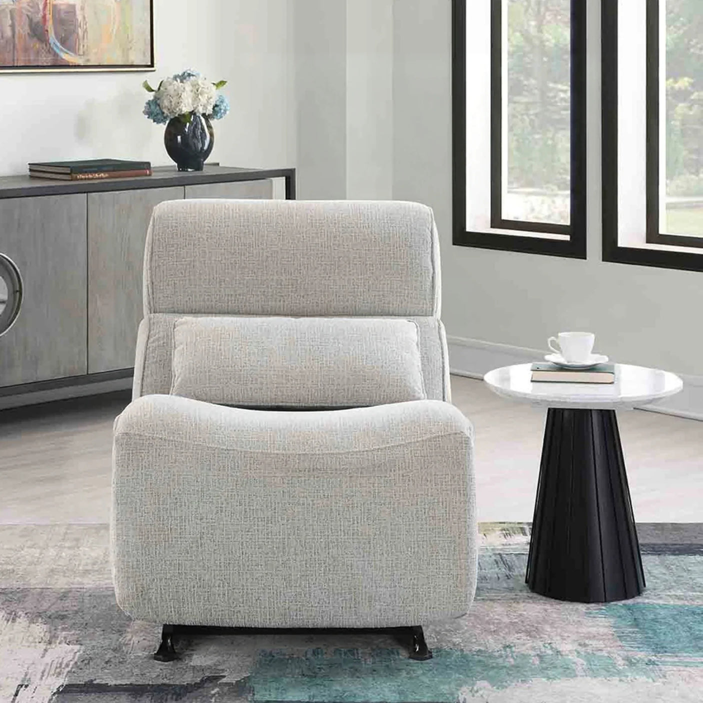 Linen manual recliner rocker chair in light grey, front view, next to a round side table