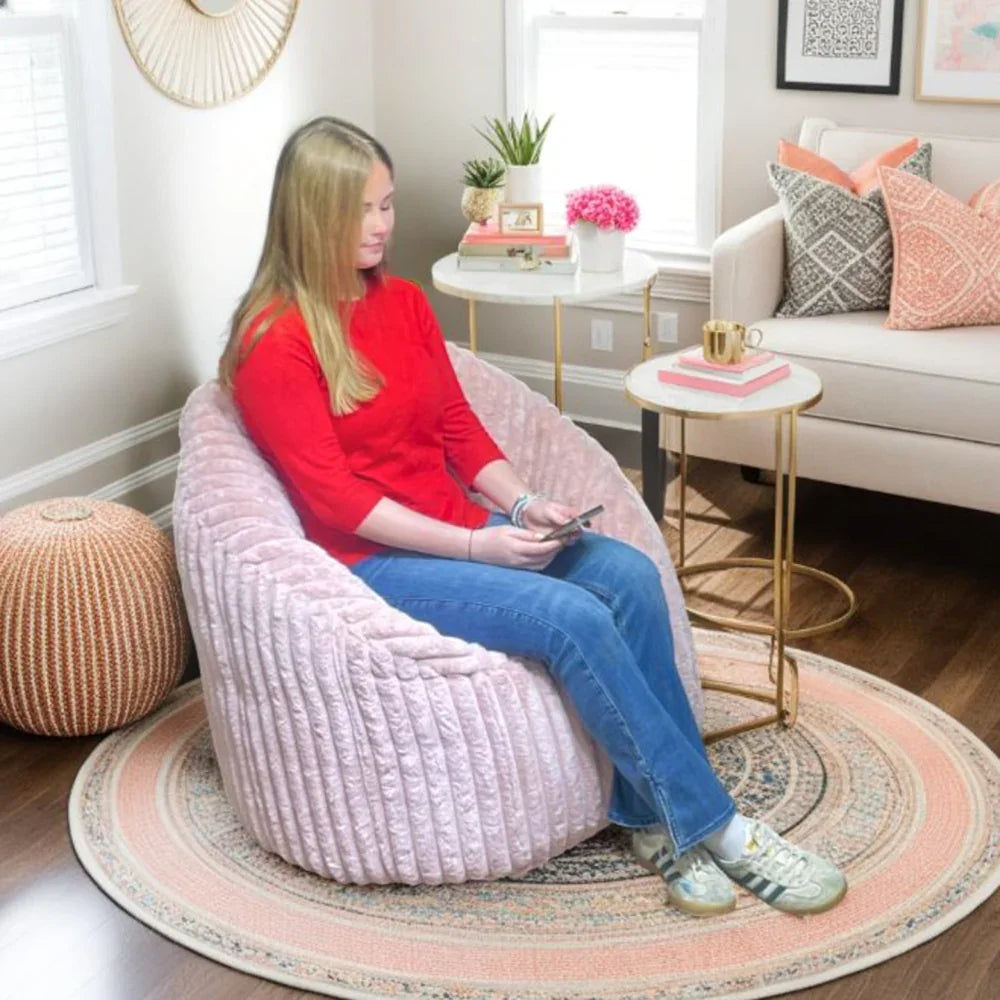 Pink cord bean bag chair in modern living room with a woman seated