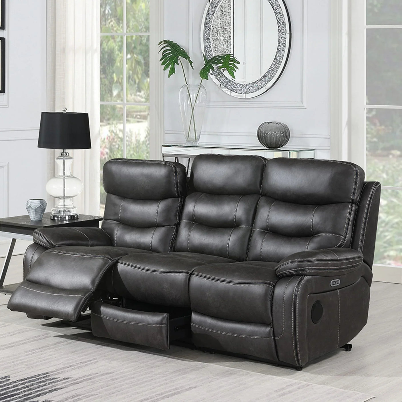 Grey three seater recliner sofa with footrest extended in bright living room setting