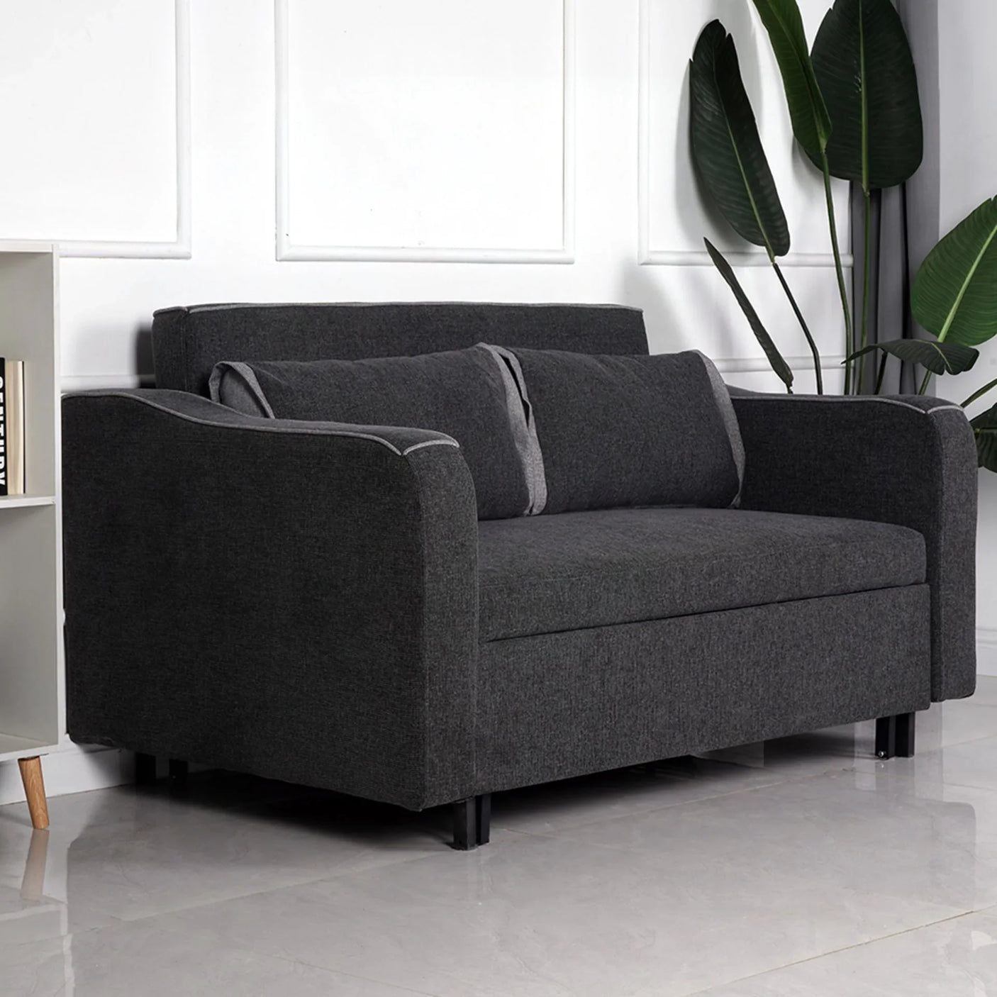 Charcoal fabric sofa bed with two matching back cushions in modern living room setting