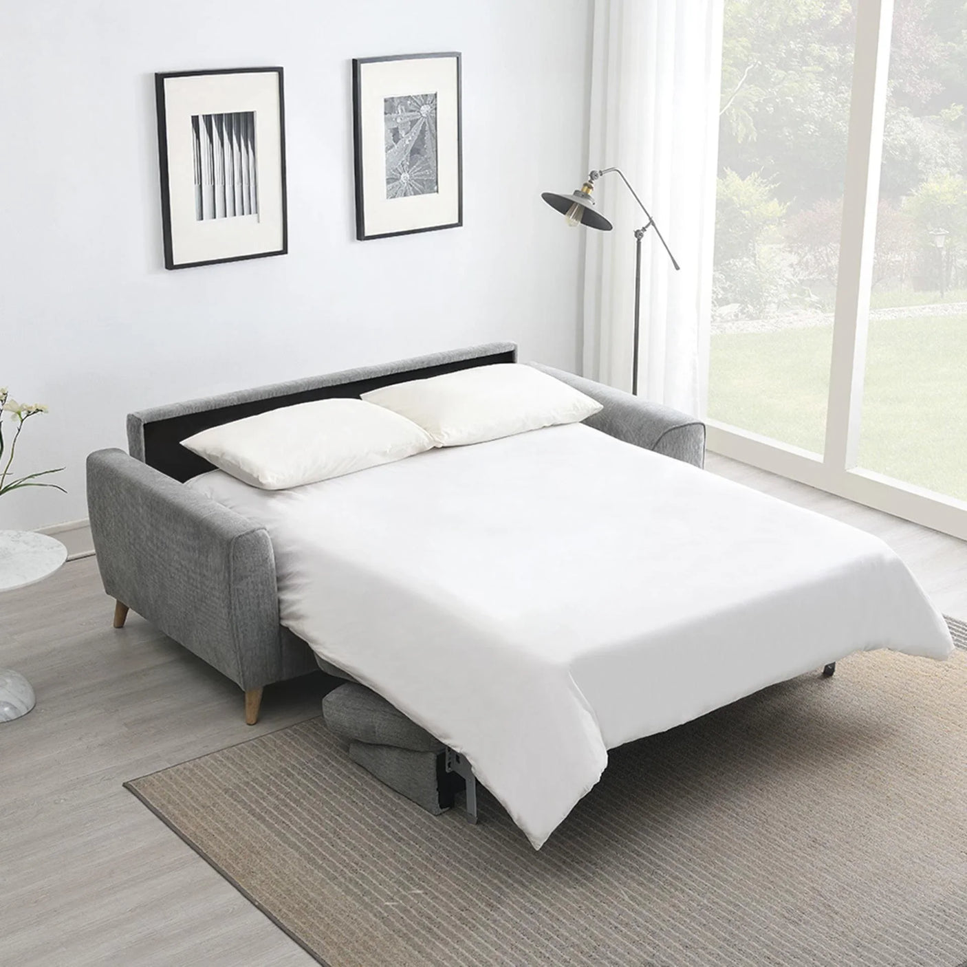 Grey fabric sofabed extended as double bed with white bedding in bright living room
