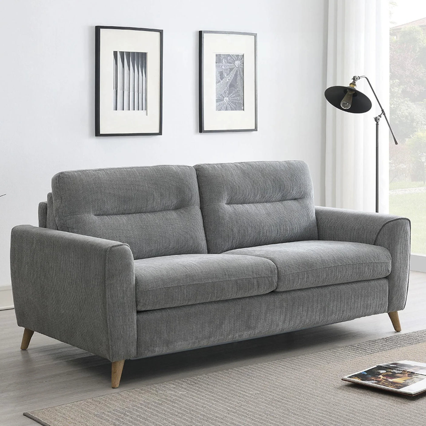 Grey fabric sofabed with wooden legs in a modern living room setting