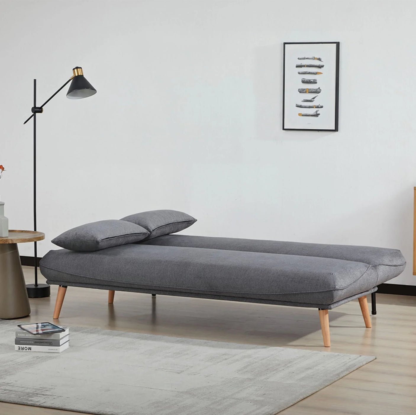 Dark grey sofa bed with wooden legs set up as a bed in modern living room setting