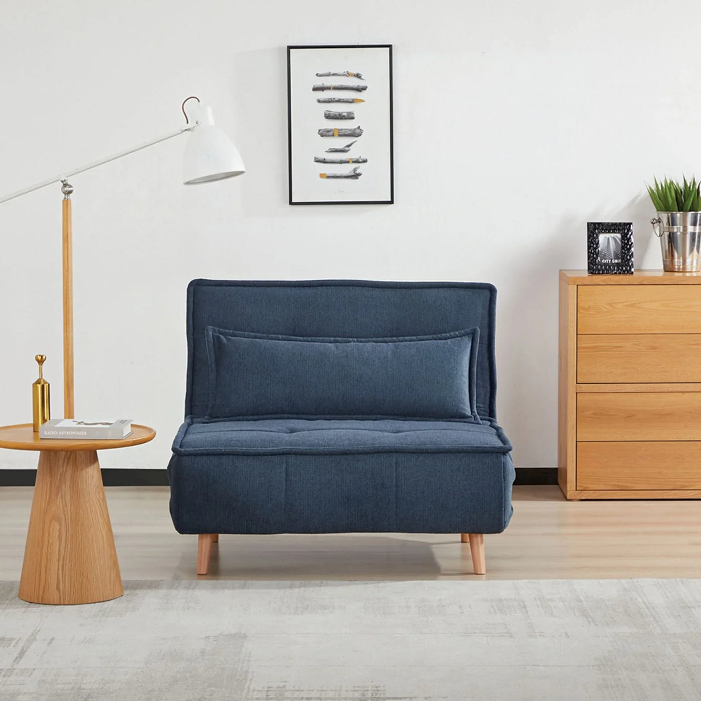 Blue fabric sofa bed with cushion, wooden legs, beside dresser in modern living room