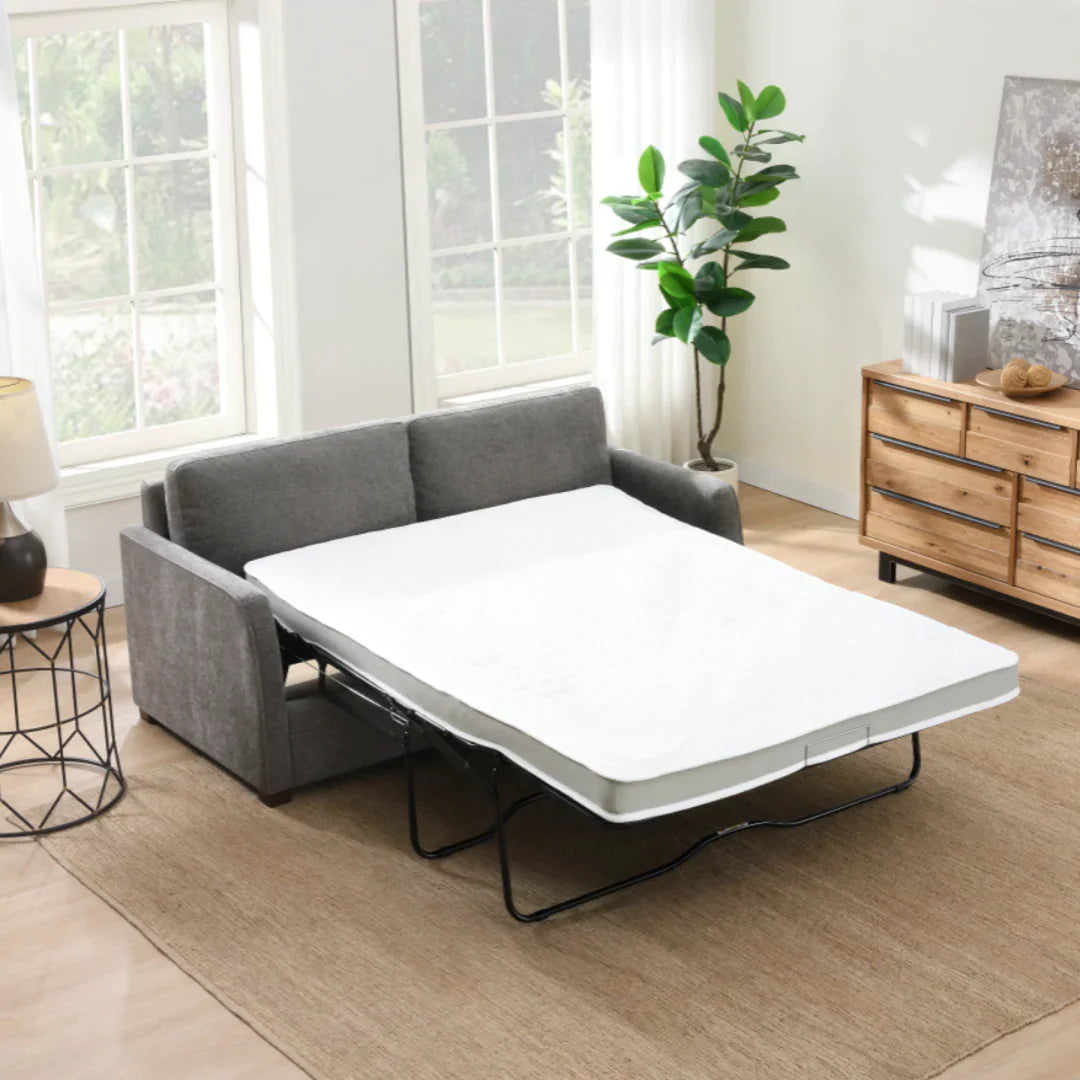 Stone foam sofa bed unfolded in bright living room with wooden dresser and indoor plant