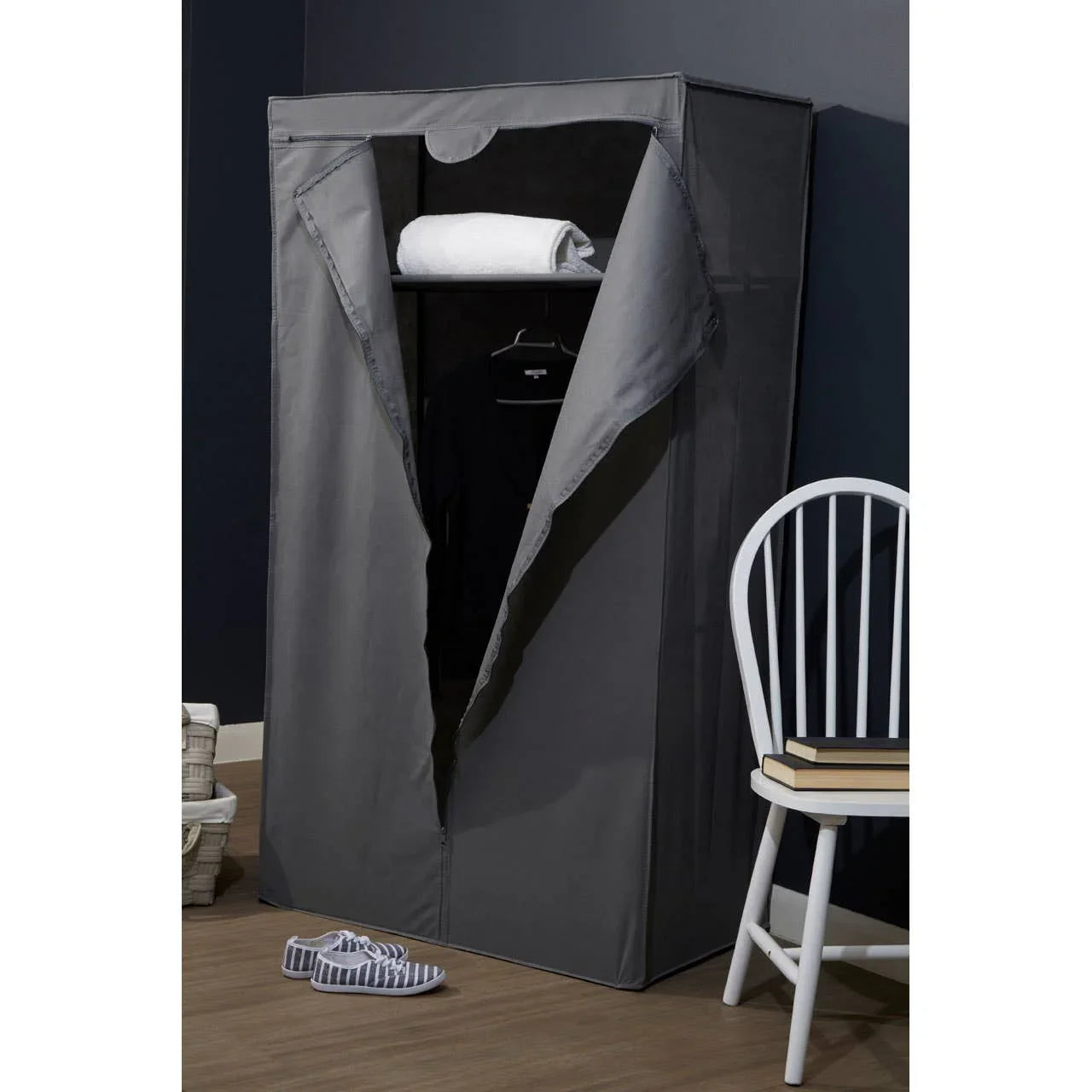 Grey fabric wardrobe with zip cover, shelf holding towel, hanging clothes, in modern room