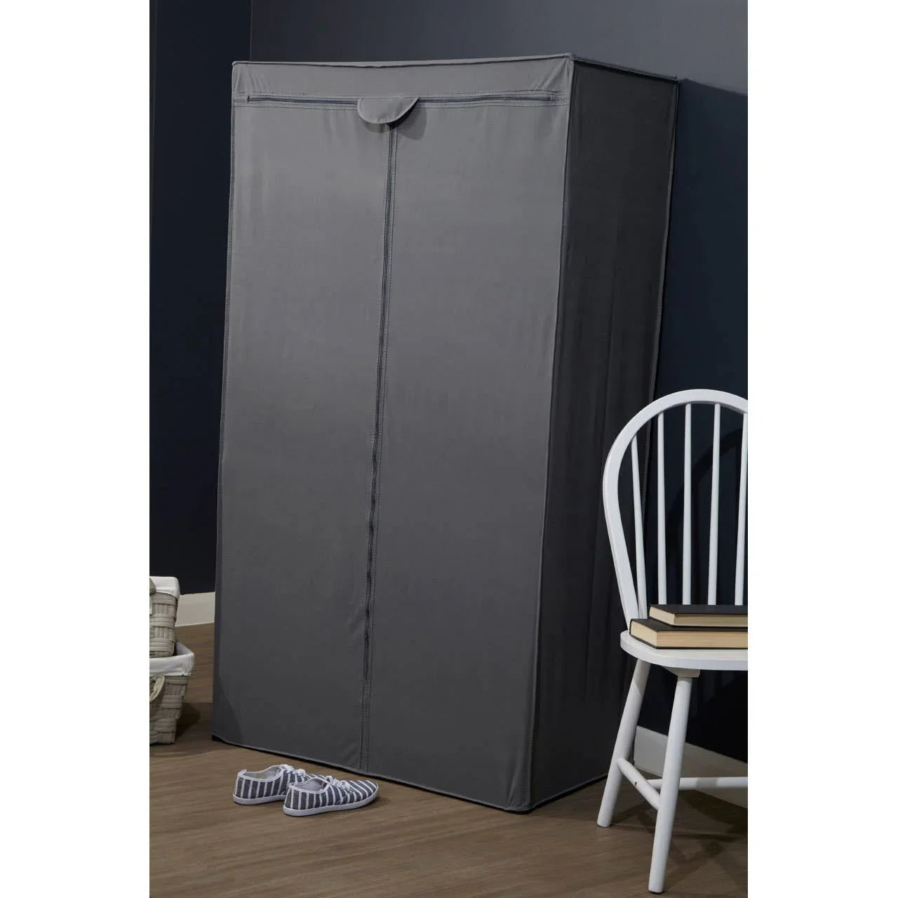 Grey fabric wardrobe organizer with zip cover in bedroom corner beside white chair